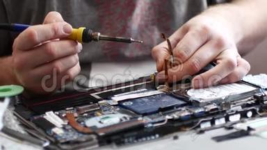 工程师在笔记本电脑上焊接电源连接器。 笔记本电脑维修保养